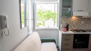 Cozinha compacta com janela, sofá e pequena área de refeições.