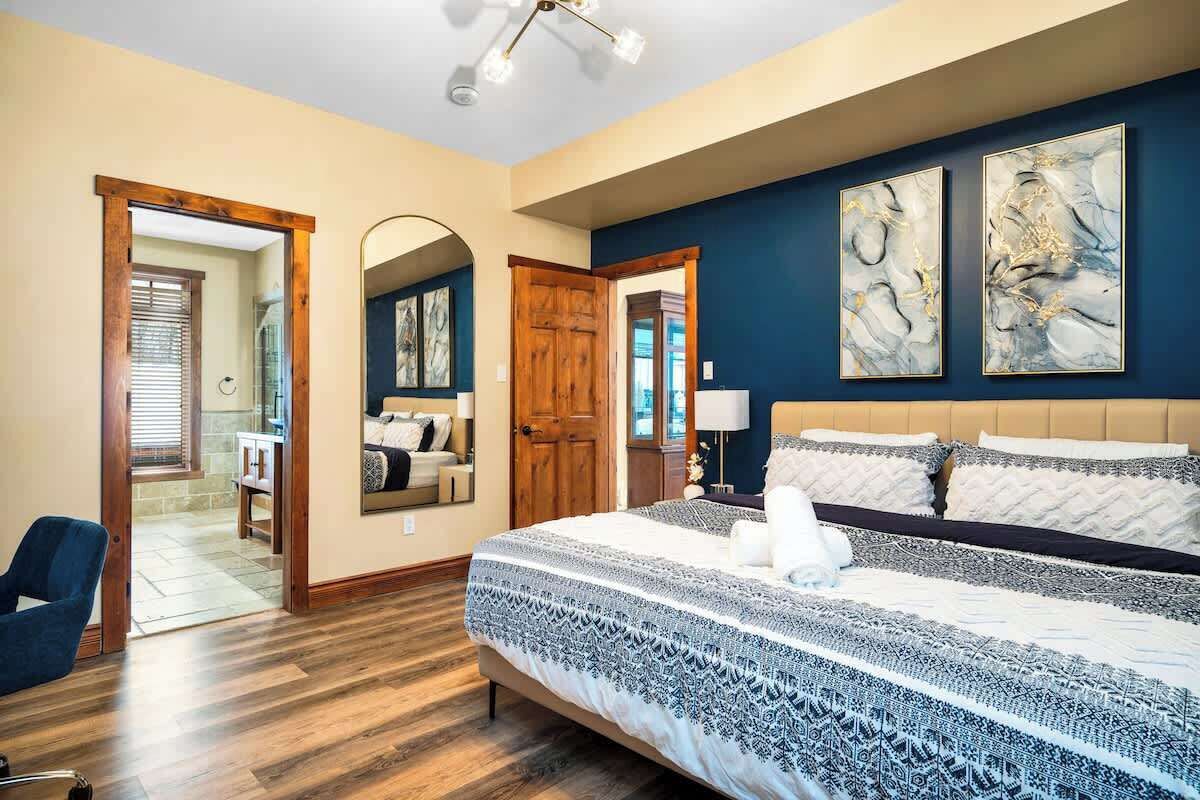 Un dormitorio con una cama grande, piso de madera y dos cuadros abstractos en la pared.