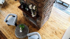 Ein Steinkamin mit Sitzgelegenheiten, einem Couchtisch und Blick auf den Wohnbereich.