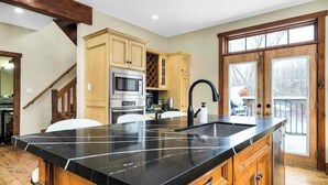 Eine Küche mit einer großen Kochinsel, Holzschränken, einem Edelstahlbackofen und einem Weinkühlschrank.