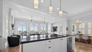 A spacious kitchen with a large island, white cabinetry, and pendant lighting. - New Beachfront Listing - Heated Pool, Golf Cart, Elevator, Steps to Best Beach (Galveston)