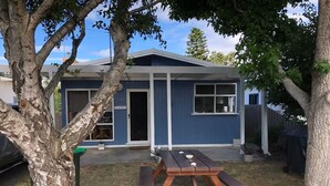 Una casa de un solo piso con fachada azul, puerta principal y puerta de garaje visible.