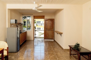 A kitchen with a refrigerator, microwave, and cabinets, leading to a balcony with a view of buildings. - Private Studio-Pool- Walk Everywhere La Punta-Kitchen & Wi-Fi-Optional Breakfast (brisas de zicatela)