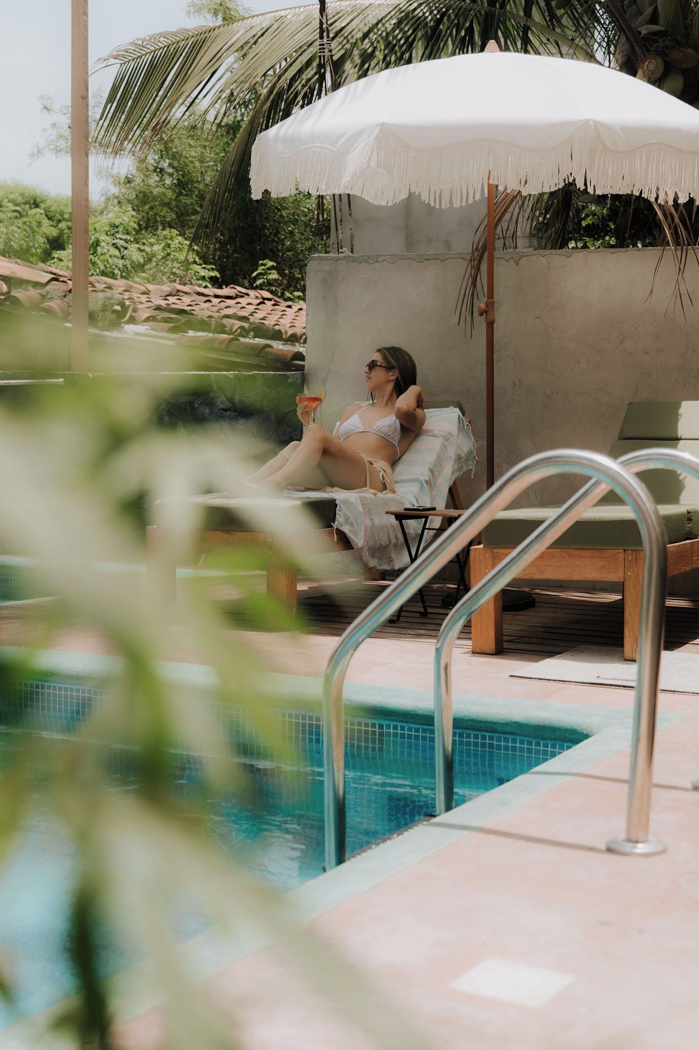 A poolside area with lounge chairs and a white umbrella.