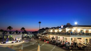 Hotel com área de estar ao ar livre, palco para música ao vivo e área de piscina.