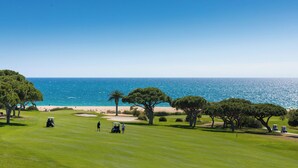 Campo de golfe com vista para o oceano e a praia.