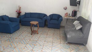 Un soggiorno con due divani blu, un divano grigio, un piccolo tavolino in legno e un pavimento decorato.