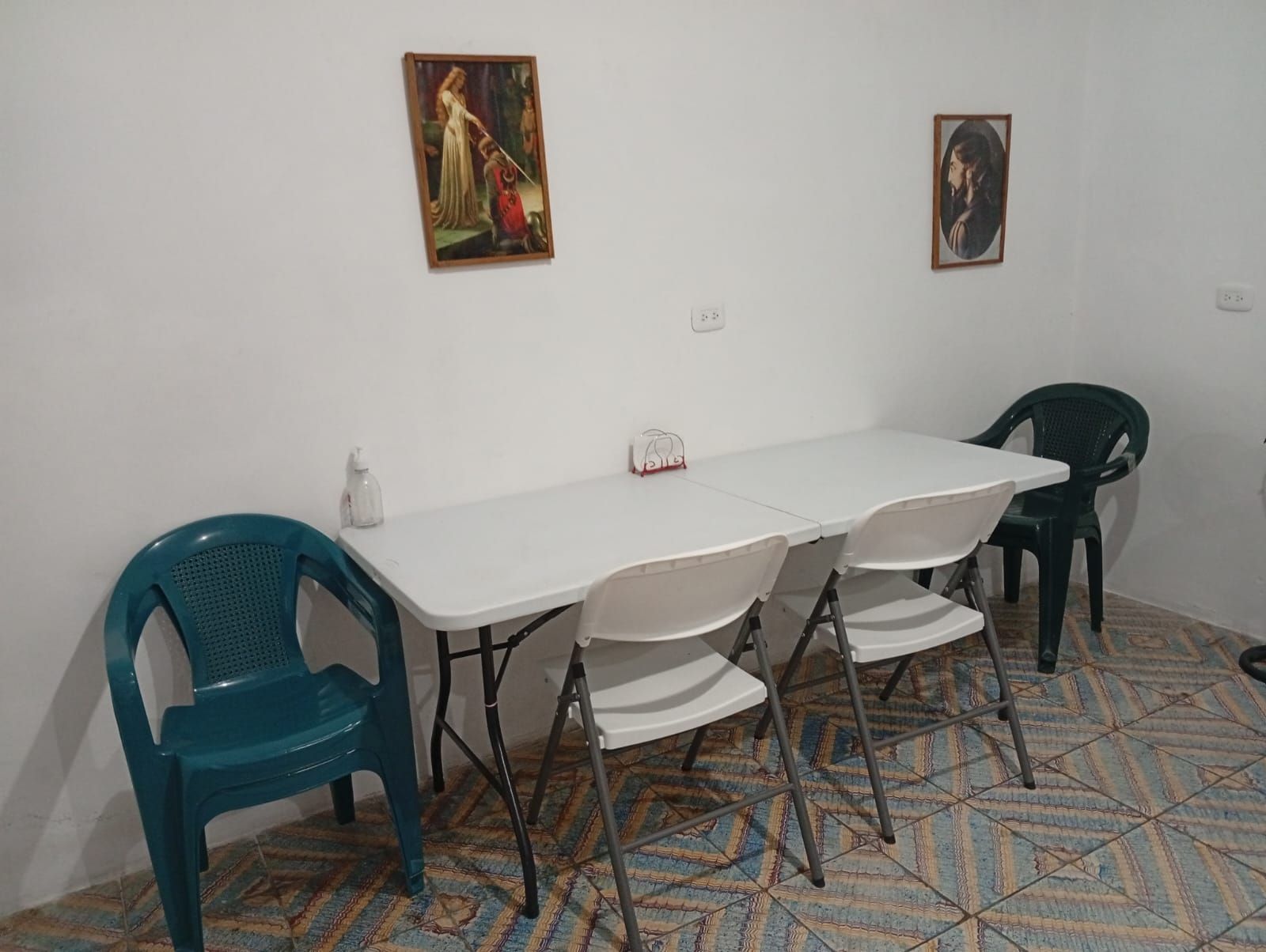 Une pièce avec une table blanche et quatre chaises, un sol à motifs et deux tableaux encadrés accrochés au mur.