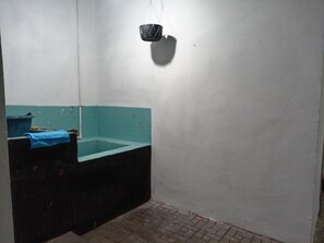 Un baño con un lavamanos azul, un cesto de basura negro y piso de baldosas.