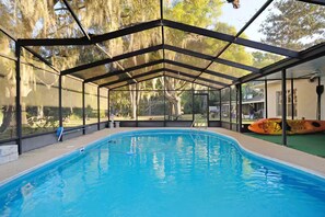 A covered swimming pool with a glass enclosure, a ladder, and a kayak. - Pool Home, Dock on the Rainbow River & 7 kayaks! (Dunnellon)