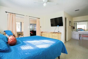A bedroom with a bed, a television, a desk, and a bathroom. - Pool Home, Dock on the Rainbow River & 7 kayaks! (Dunnellon)