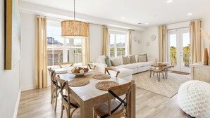 A spacious living area with a dining table, sofa, and a balcony view. - Sea La Vie Corner Condo at Gulf Place Wraparound Balcony & Beach Access (Santa Rosa Beach)