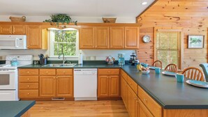A kitchen with wooden cabinets, a dishwasher, a microwave, and a sink. - Breathtaking Views for Family & Friends to Gather (Clarkesville)