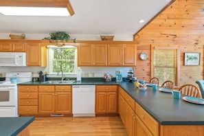 A kitchen with wooden cabinets, a dishwasher, a microwave, and a sink. - Breathtaking Views for Family & Friends to Gather (Clarkesville)