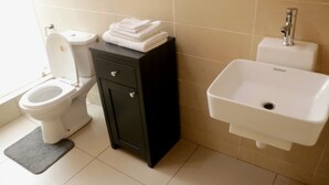 A bathroom with a toilet, a black cabinet, and a white sink. - Spacious family house (Com-25 TEMA) near beaches with comfort and security. (Acca)