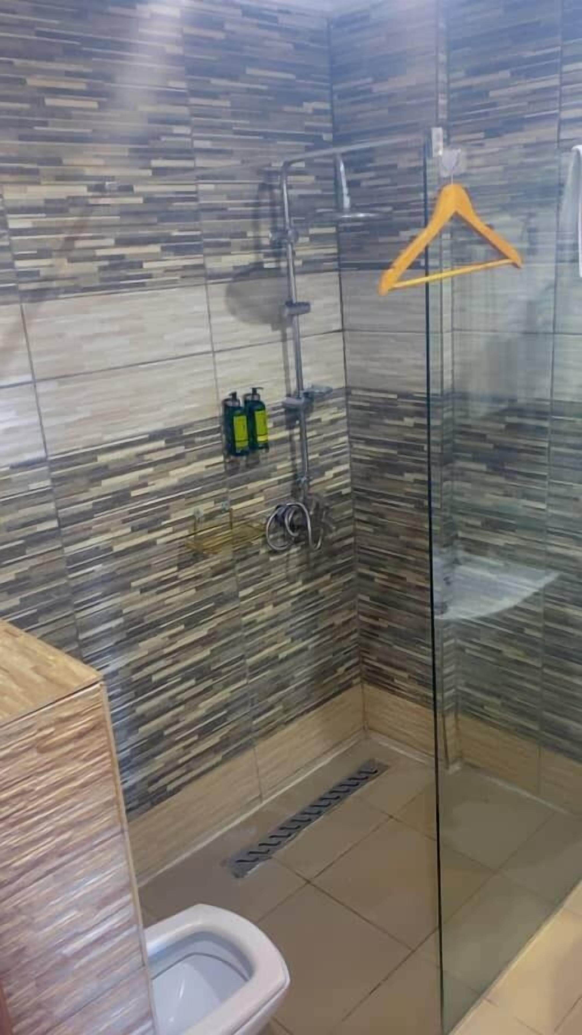 A bathroom with a glass shower enclosure, a toilet, and a sink.