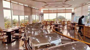 Un restaurante con mesas largas, sillas y vistas al exterior.