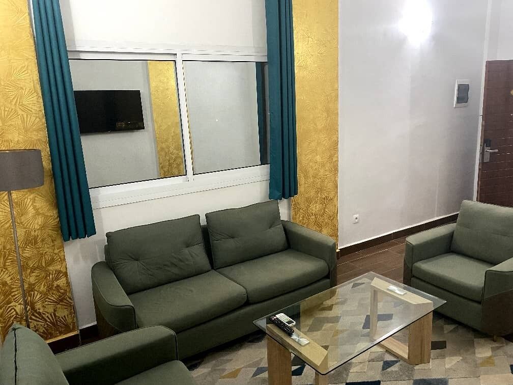 Un soggiorno con divano, poltrone e tavolino in vetro.