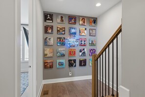 Ein Gang mit einer Wand, die mit verschiedenen Schallplattenbildern und einem Neonzeichen dekoriert ist.