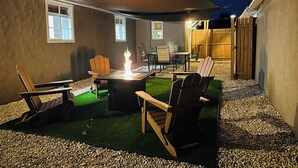 Un patio al aire libre con un pozo de fuego, asientos y una zona cubierta.
