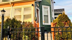 Una casa de dos pisos con un porche delantero, un buzón y un pequeño jardín con cerca.