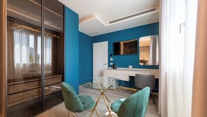 A modern hotel room with a blue accent wall, a glass table with four chairs, a large mirror, and a wardrobe with sliding doors. - MW apartments (Milan)