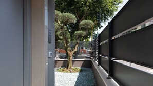 A narrow outdoor corridor with a metal railing, a tree, and a gravel path. - MW apartments (Milan)