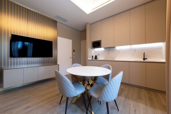 A modern kitchen with a round dining table and four chairs, a built-in microwave, and a TV mounted on the wall. - MW apartments (Milan)