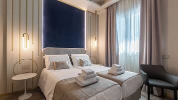 Ein modernes Hotelzimmer mit zwei Betten, einem runden Tisch, einem Stuhl und einem großen Fenster mit Vorhängen.