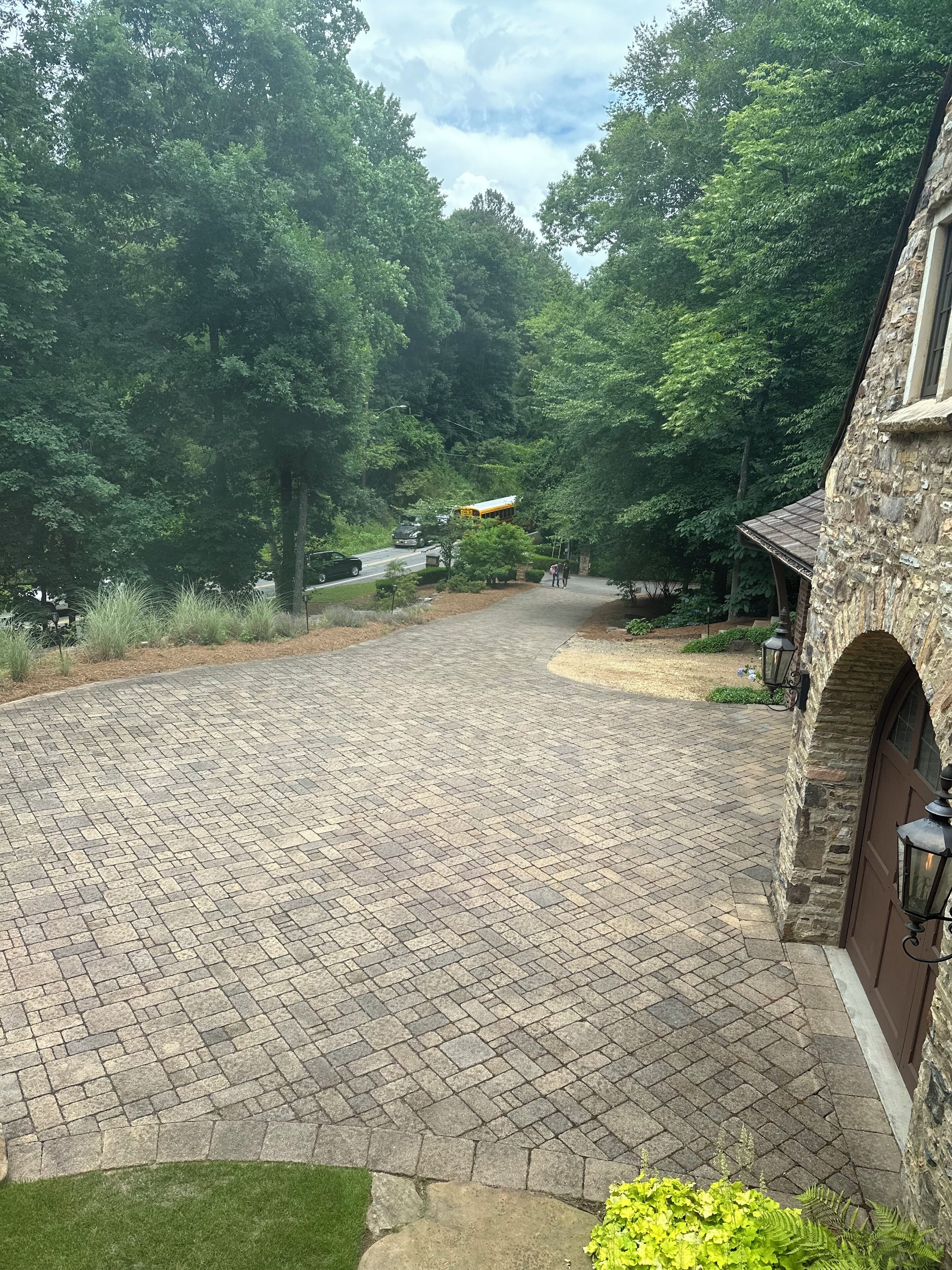 A paved driveway leading to a stone building with a covered porch.
