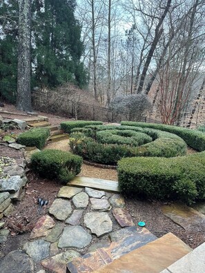 A garden with a stone pathway, neatly trimmed hedges, and a metal fence. - 2-bedroom apartment in amazing Marietta with AC and comfort (Marietta)