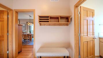 A hallway with wooden doors, a bench, and a wall-mounted shelf unit.