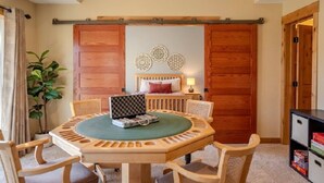 A room with a round wooden table, four chairs, a bed with a headboard, a bedside table with a lamp, and a sliding wooden door. - Spacious Modern 5-Bed Home –  Near Twin Cities (Rosemount)