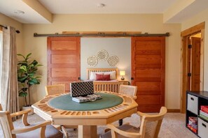 A room with a round wooden table, four chairs, a bed with a headboard, a bedside table with a lamp, and a sliding wooden door. - Spacious Modern 5-Bed Home –  Near Twin Cities (Rosemount)
