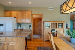 A kitchen with wooden cabinets, a granite countertop, and a dining area with a bench. - Spacious Modern 5-Bed Home –  Near Twin Cities (Rosemount)