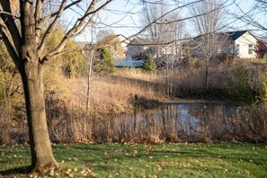 A pond surrounded by trees and grass, with houses in the background. - Spacious Modern 5-Bed Home –  Near Twin Cities (Rosemount)