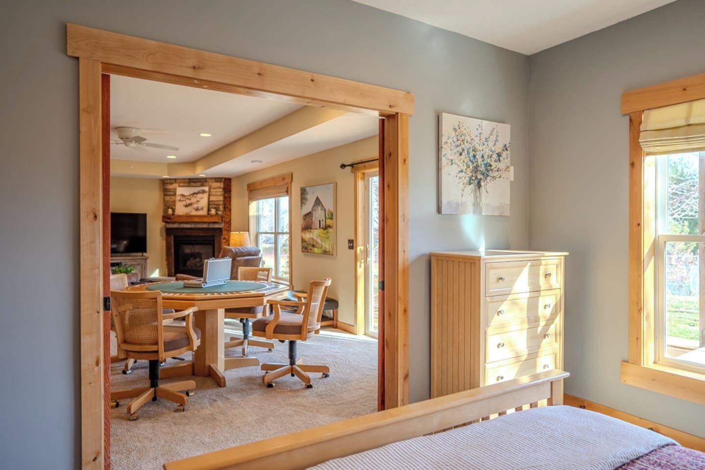 A bedroom with a bed, a desk with chairs, a dresser, and a painting on the wall.