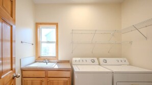 A laundry room with a sink, wooden cabinets, and three stacked washers and dryers. - Spacious Modern 5-Bed Home –  Near Twin Cities (Rosemount)