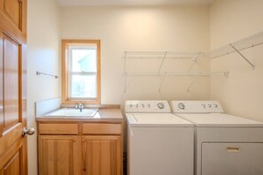 A laundry room with a sink, wooden cabinets, and three stacked washers and dryers. - Spacious Modern 5-Bed Home –  Near Twin Cities (Rosemount)