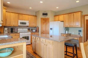 A kitchen with wooden cabinets, a microwave, stove, refrigerator, and a clock on the wall. - Spacious Modern 5-Bed Home –  Near Twin Cities (Rosemount)