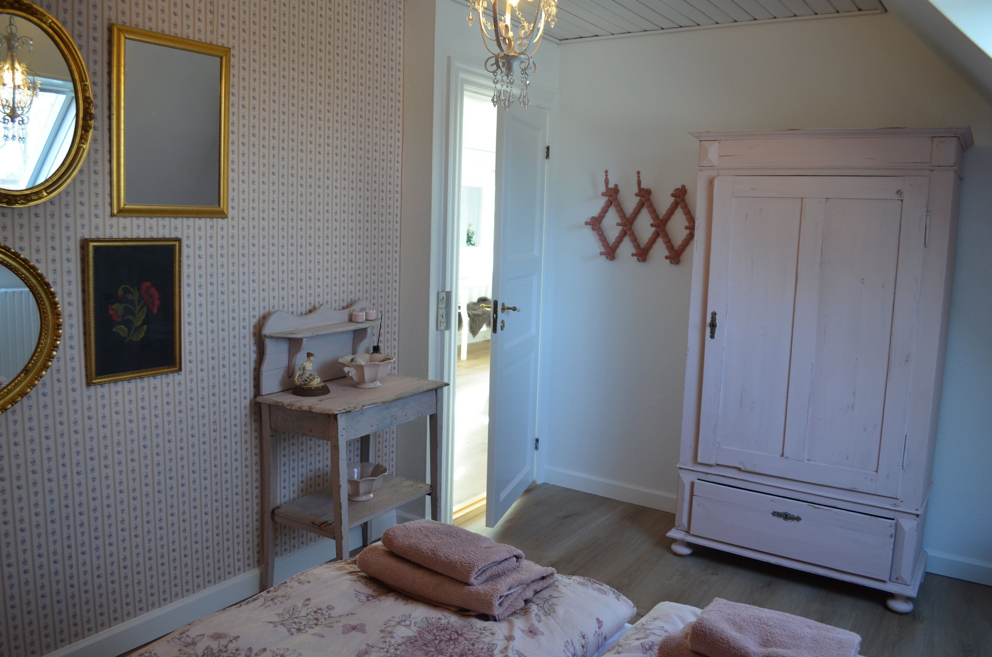 A bedroom with a bed, a dresser, a mirror, and a door leading to another room.