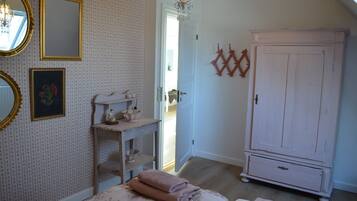 A bedroom with a bed, a dresser, a mirror, and a door leading to another room.
