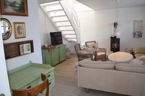A loft-style room with a sloped ceiling, a television, wicker furniture, and a sofa.