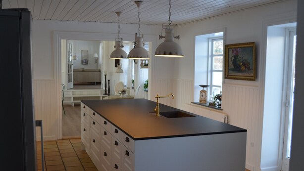 Een keuken met een centraal eiland, hanglampen, een spoelbak en een raam met uitzicht.