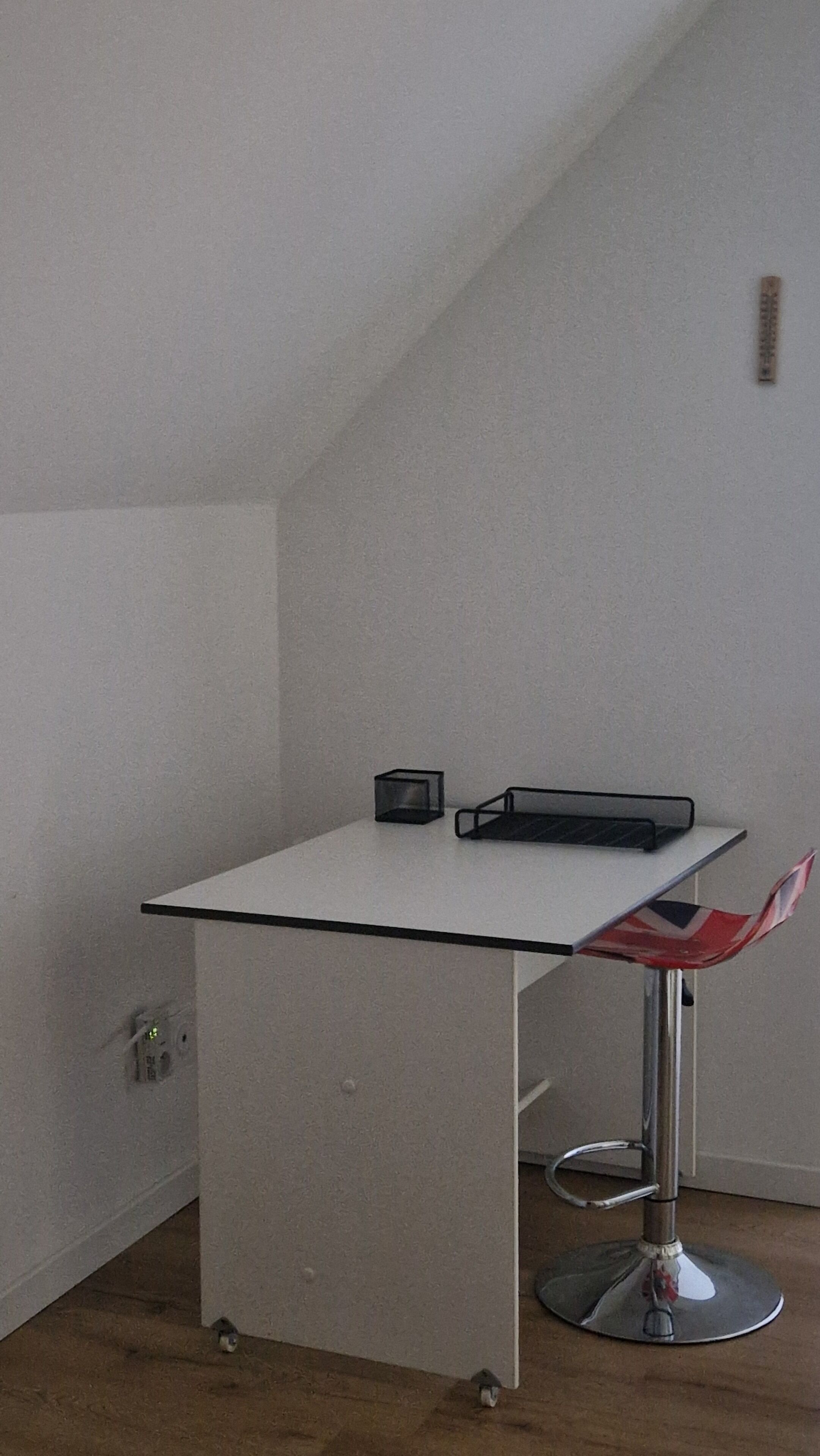 A small, white, rectangular table with a black metal frame and a red and white chair.