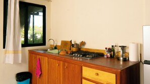 A kitchen with a wooden countertop, a gas stove, a sink, and a window with a view of greenery. - Private Studio Palapa Mango- Pool- Ocean View - La Punta (brisas de zicatela)