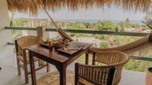 A wooden table with chairs and a hammock in a room with a view of the ocean. - Private Studio Palapa Mango- Pool- Ocean View - La Punta (brisas de zicatela)