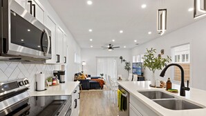 A modern kitchen with a central island, stainless steel appliances, and a dining area with a sofa and table. - 3BR King Bed • Pet Friendly • Near Alamodome (San Antonio)