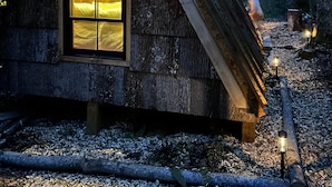 Une petite cabane en bois, dotée d’un toit triangulaire et d’une grande fenêtre.