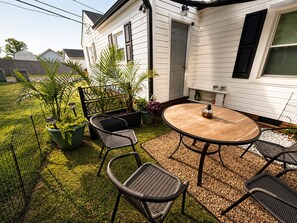 A patio with a round table and four chairs, surrounded by potted plants and a small garden.